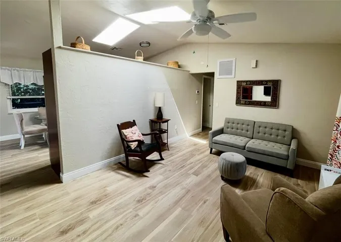 Living area with wood finished floors, a ceiling fan, baseboards, and lofted ceiling