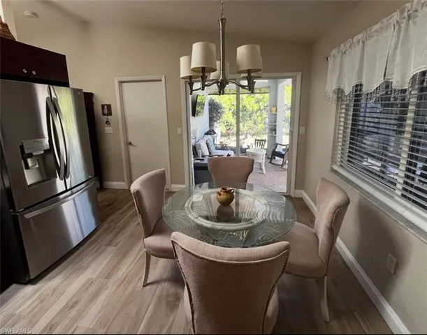 Dining area with a chandelier, light wood-type flooring, baseboards, and vaulted ceiling