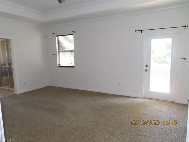 Empty room featuring light colored carpet and ornamental molding