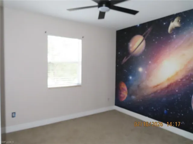 Carpeted empty room with ceiling fan and an accent wall