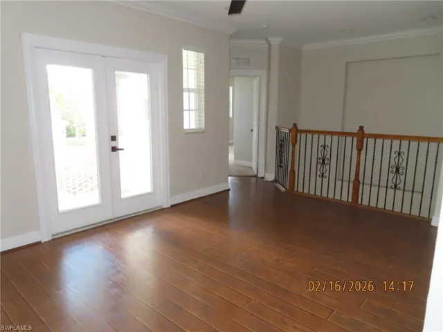 Spare room featuring french doors, crown molding, and dark wood-type flooring