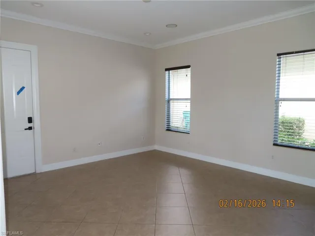 Unfurnished room with ornamental molding and light tile patterned flooring