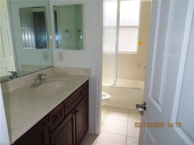 Bathroom with vanity, light tile patterned floors, and shower / bath combination with glass door