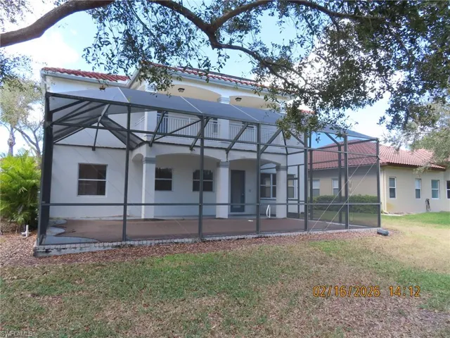 Back of property with glass enclosure, stucco siding, a tile roof, a yard, and a sunroom