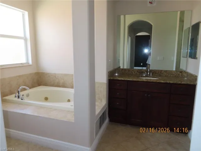 Bathroom featuring vanity, a whirlpool tub, and light tile patterned floors