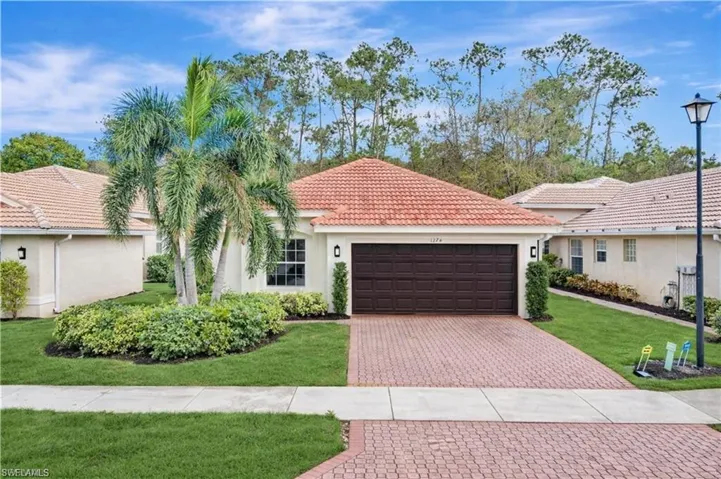 Mediterranean / spanish-style home featuring a front lawn, a garage, stucco siding, driveway, and a tile roof