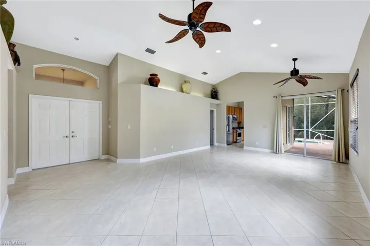 Unfurnished living room with ceiling fan, vaulted ceiling, light tile patterned floors, and recessed lighting