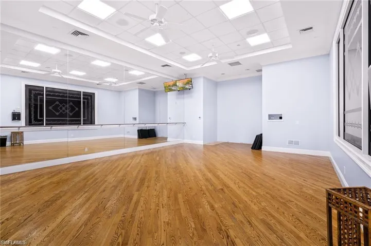 Workout room with a ceiling fan, a drop ceiling, and a raised ceiling