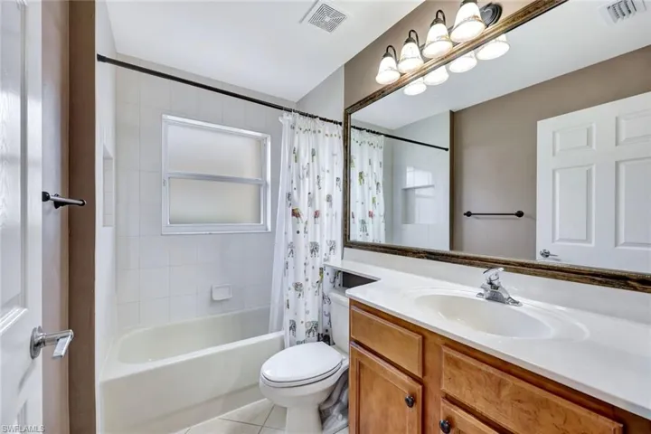 Full bathroom featuring vanity, shower / bathtub combination with curtain, and light tile patterned flooring