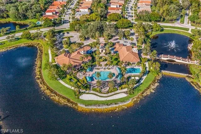 Aerial view of property and surrounding area with a nearby body of water and a pool area