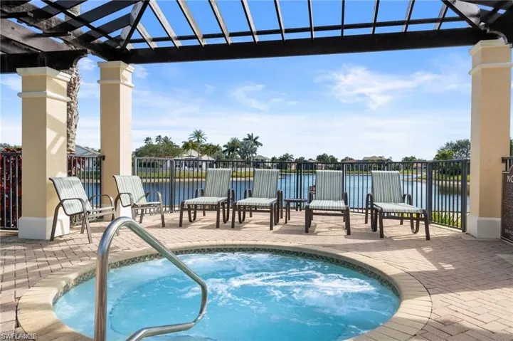 View of swimming pool with a pergola, a community hot tub, patio surround, and a water view