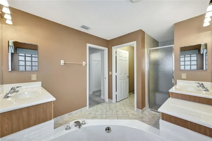 Bathroom featuring two vanities, a stall shower, and a bath