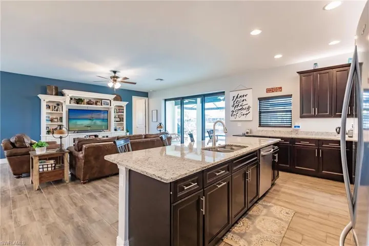 Kitchen with ceiling fan, plank tile floors, sink, a kitchen island with sink, and appliances with stainless steel finishes