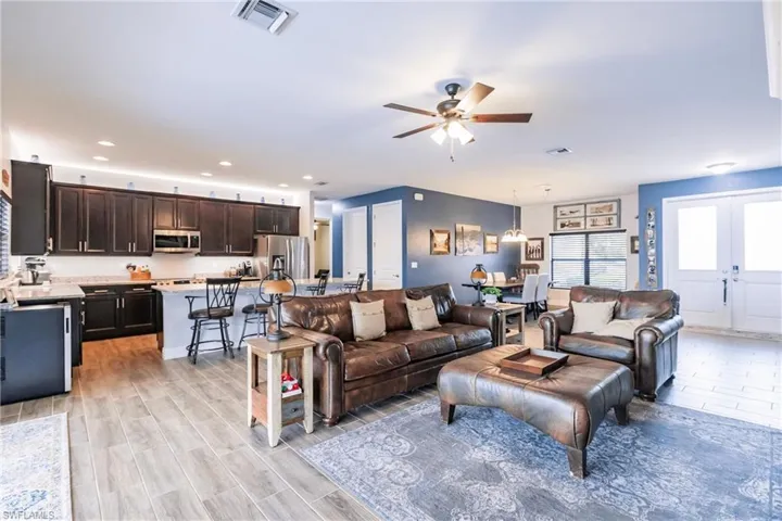Living room featuring french doors, ceiling fan, and plank tile flooring
