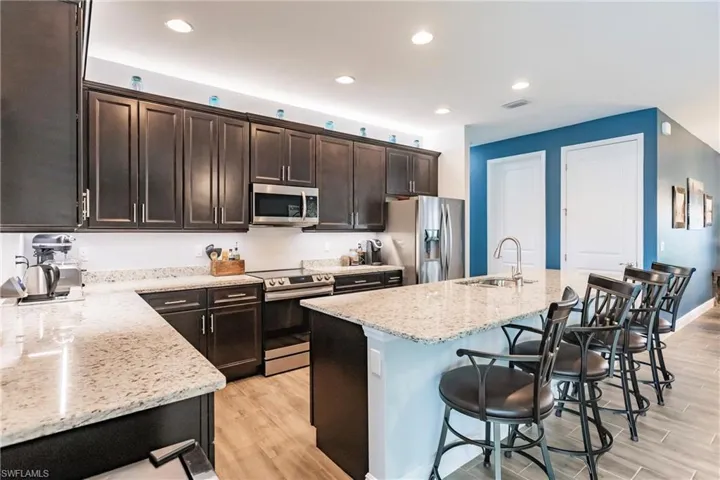 Kitchen featuring a breakfast bar area, appliances with stainless steel finishes, sink, and plank tile flooring