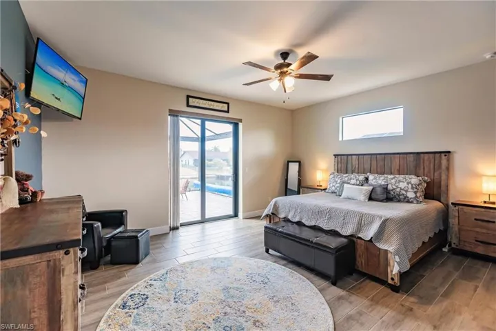 Bedroom featuring plank tile flooring, ceiling fan, access to outside, and multiple windows