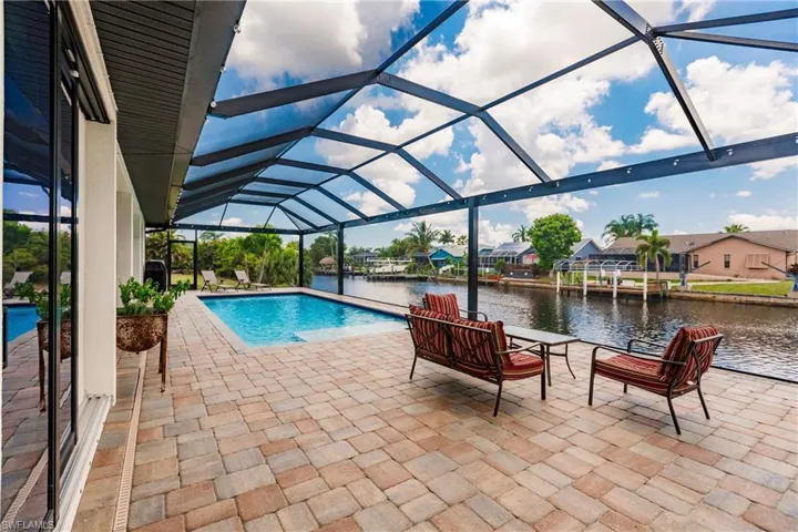 View of pool and sunsets with a patio area, a lanai, and a water view