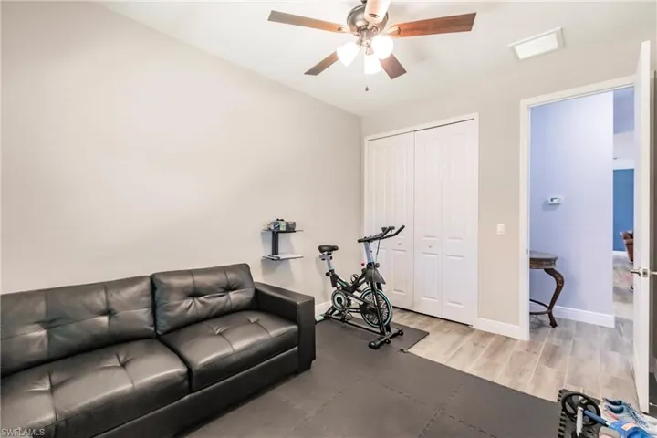 Guest bedroom/exercise area with ceiling fan and plank tile flooring