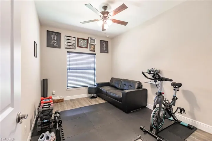 Guest bedroom/exercise area featuring plank tile floors and ceiling fan