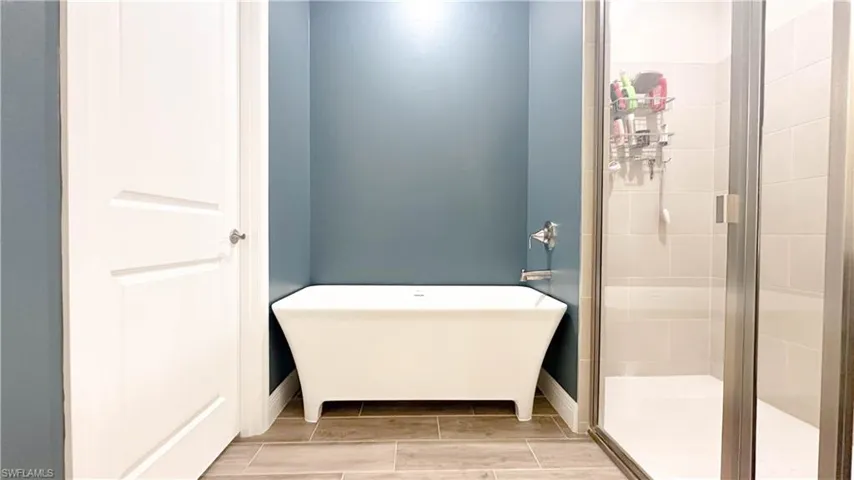 Bathroom with a shower with shower door and tile flooring
