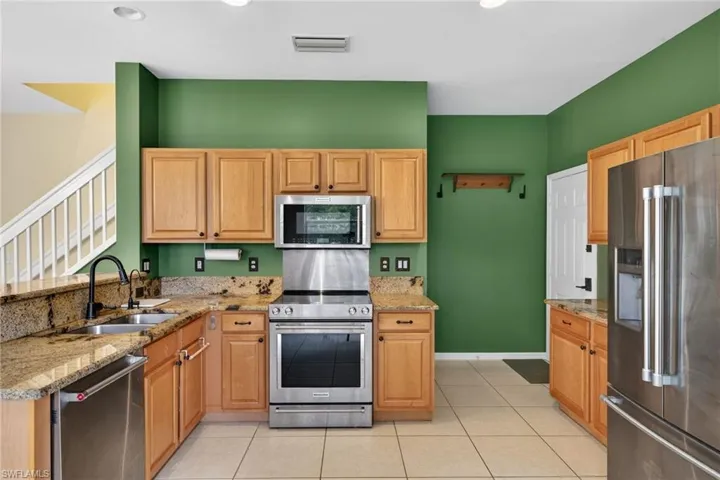 Kitchen with stainless steel appliances, light stone countertops, light tile patterned floors, and a peninsula