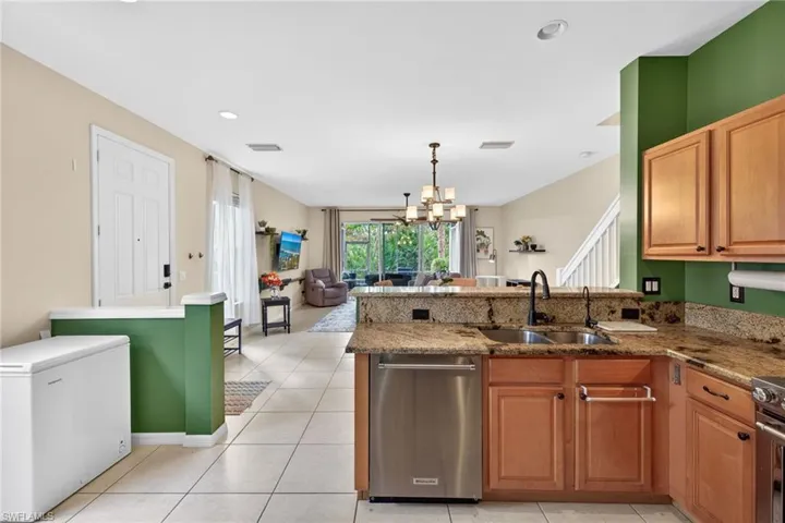 Kitchen with a chandelier, open floor plan, a peninsula, stainless steel appliances, and dark stone counters