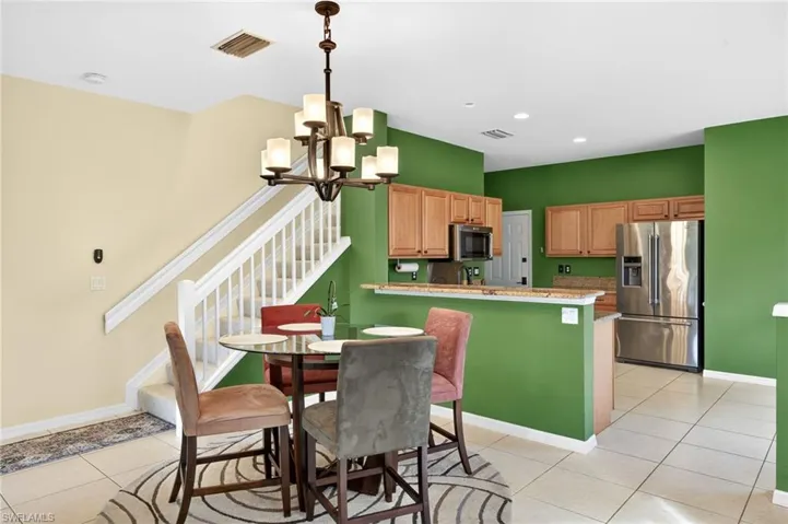 Dining area featuring stairway, light tile patterned flooring, a chandelier, and recessed lighting