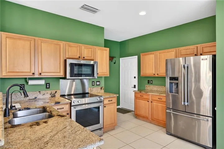 Kitchen featuring appliances with stainless steel finishes, light stone countertops, light brown cabinets, light tile patterned flooring, and recessed lighting