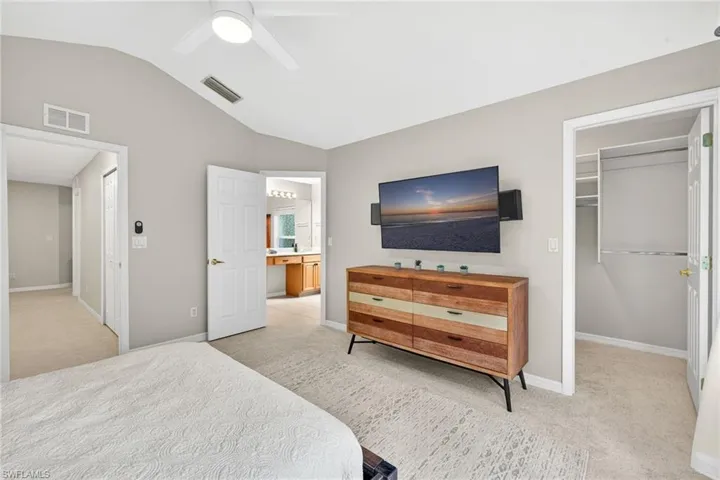 Bedroom featuring light carpet, lofted ceiling, a spacious closet, and ceiling fan