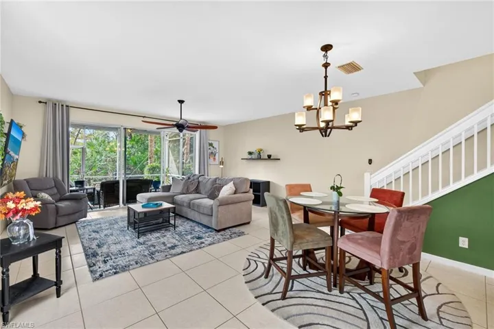 Dining area featuring light tile patterned floors, a chandelier, ceiling fan, and stairway