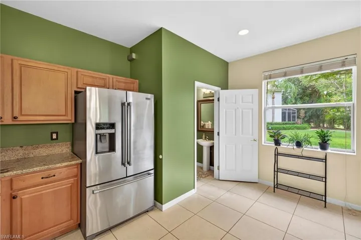 Kitchen featuring light stone countertops, stainless steel fridge, and light tile patterned floors