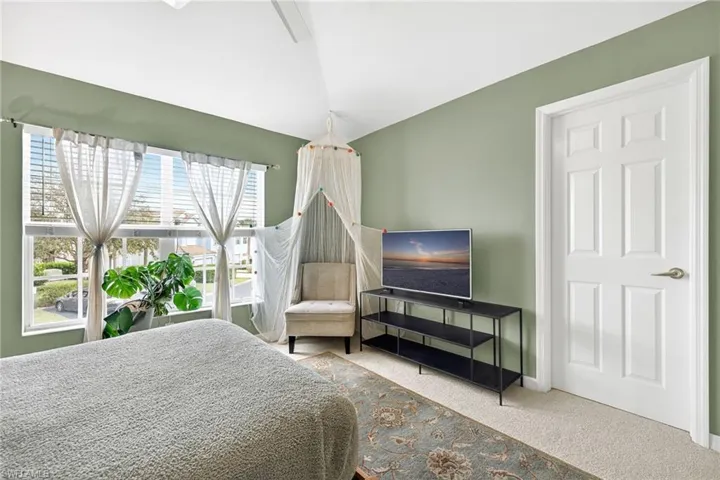 Carpeted bedroom featuring lofted ceiling and ceiling fan