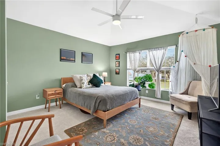 Carpeted bedroom with ceiling fan and lofted ceiling