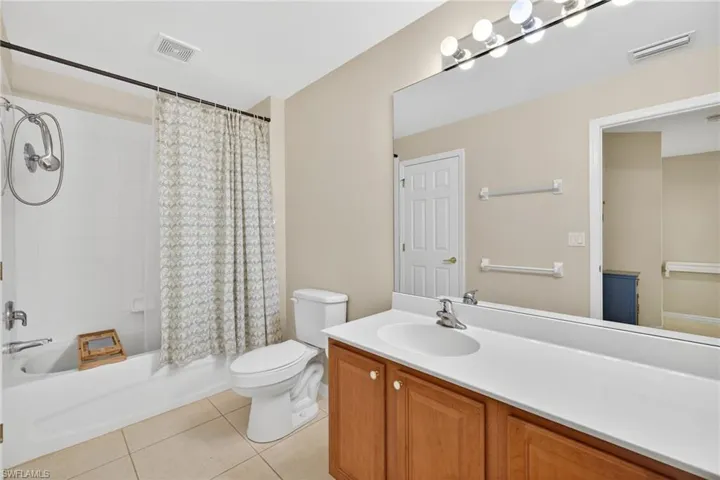 Bathroom with vanity, shower / tub combo with curtain, and light tile patterned floors