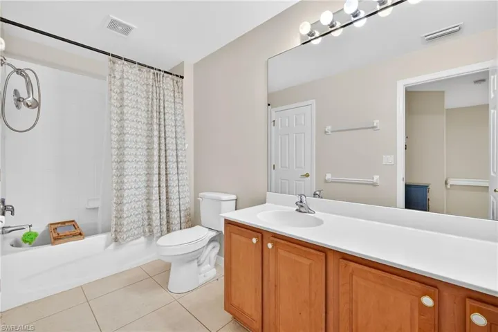 Full bath featuring vanity, shower / bath combo with shower curtain, and light tile patterned floors