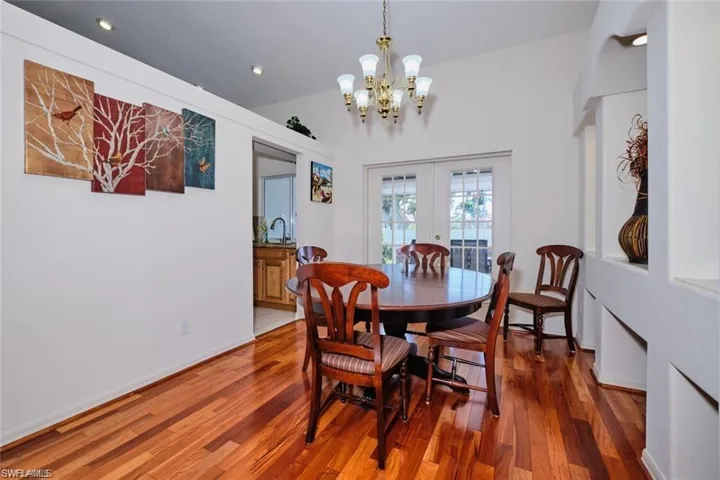 Dining space featuring vaulted ceiling, an inviting chandelier, recessed lighting, french doors, and wood finished floors