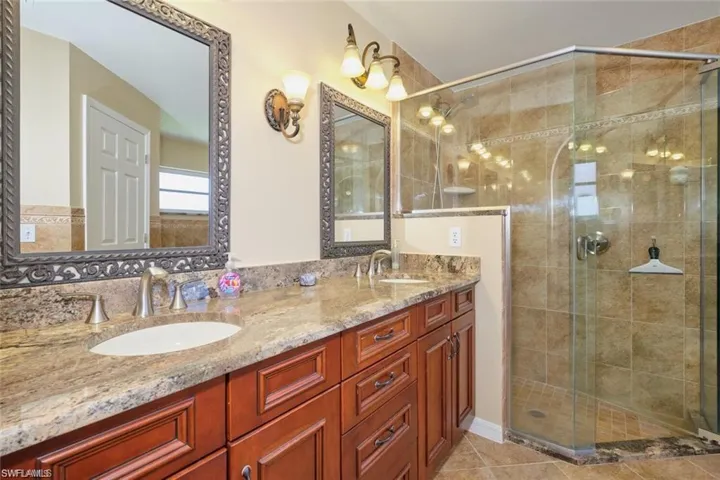 Bathroom featuring a stall shower, double vanity, and a sink