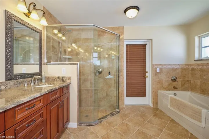 Full bathroom featuring tile patterned flooring, a bath, a stall shower, and vanity