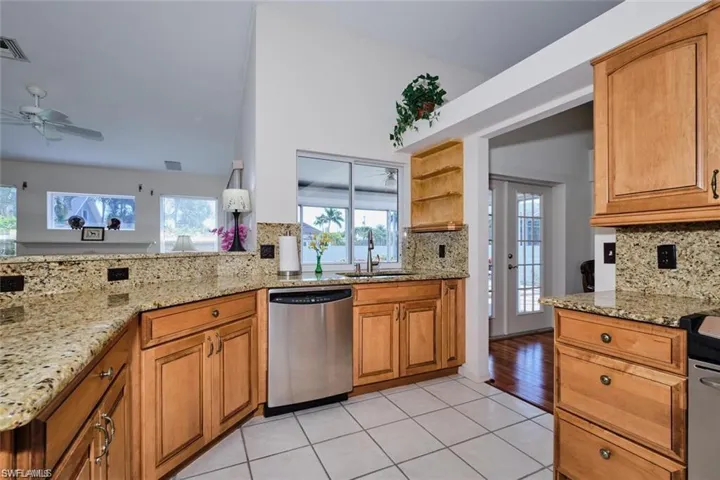 Kitchen featuring decorative backsplash, light stone counters, and dishwasher