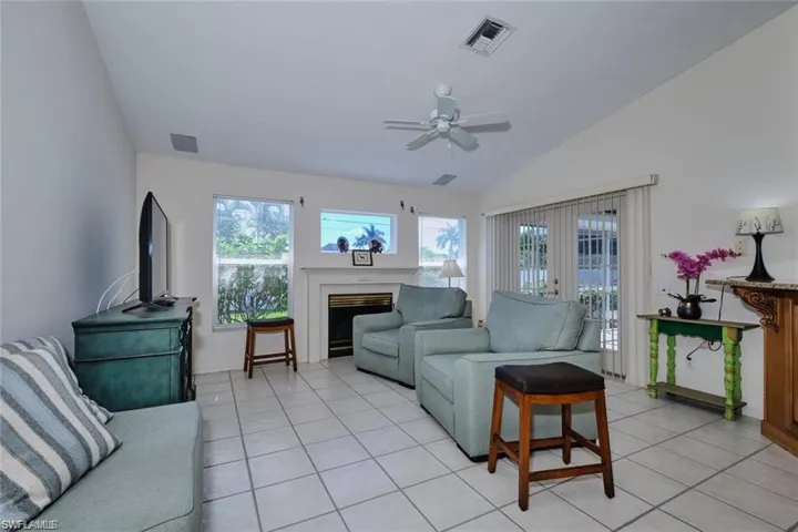 Living area featuring light tile patterned floors, visible vents, vaulted ceiling, and ceiling fan