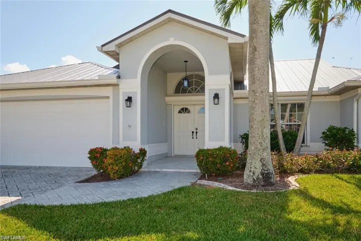 View of exterior entry with metal roof, stucco siding, driveway, and a garage