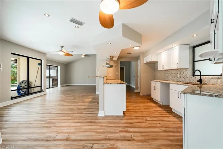 Kitchen featuring light stone counters, light hardwood / wood-style flooring, sink, and white cabinetry