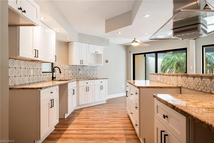 Kitchen with light stone countertops, sink, light hardwood / wood-style floors, and white cabinets
