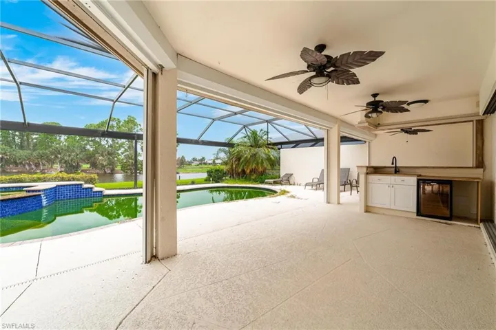 View of patio with a water view, ceiling fan, a pool with hot tub, a lanai, and wine cooler