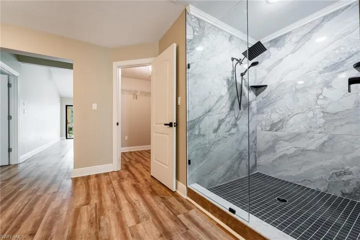 Bathroom featuring wood-type flooring, ornamental molding, and tiled shower