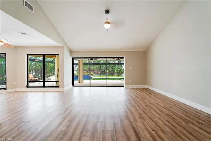 Empty room featuring lofted ceiling, ceiling fan, and light hardwood / wood-style flooring