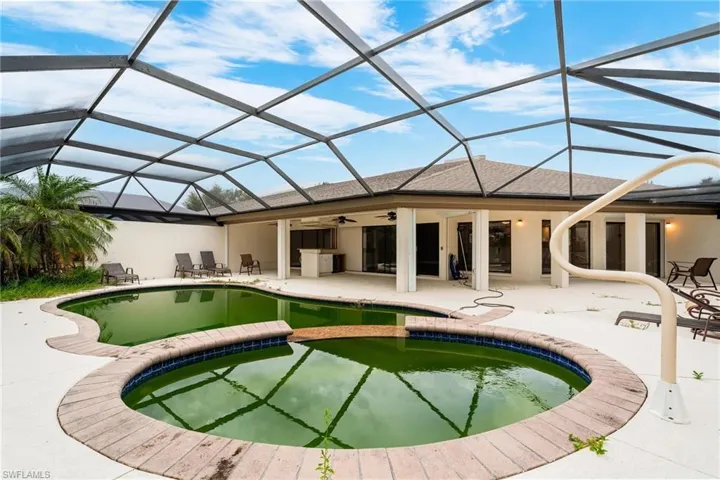 Rear view of house with ceiling fan, a pool with hot tub, a patio, and a lanai