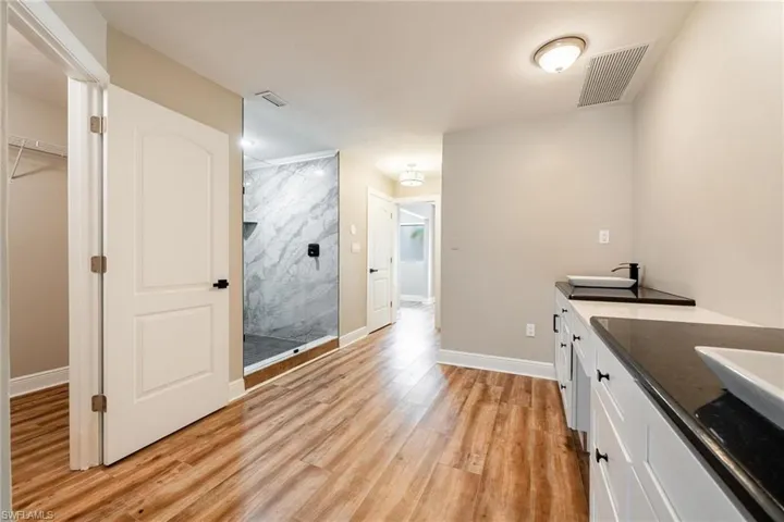 Bathroom with wood-type flooring, vanity, and a tile shower