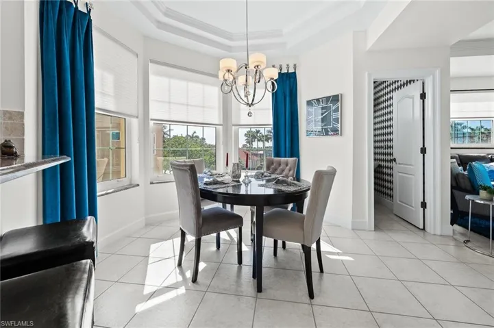 Dining space with light tile patterned floors, suspended lighting, and crown molding