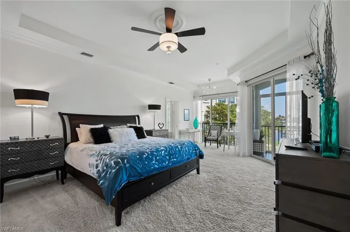Bedroom featuring crown molding, carpet floors, access to exterior, a raised ceiling, and a ceiling fan